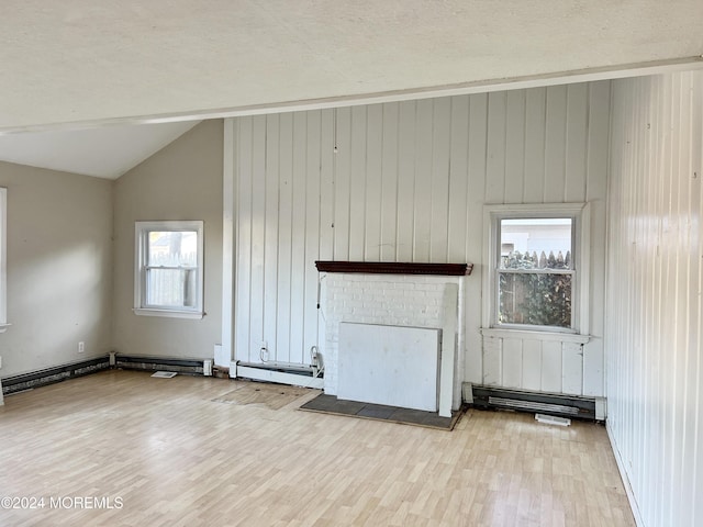 unfurnished living room with a healthy amount of sunlight, wood walls, light hardwood / wood-style floors, and lofted ceiling