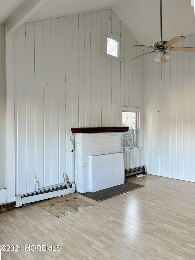 unfurnished living room with light wood-type flooring, a baseboard radiator, lofted ceiling, and wood walls