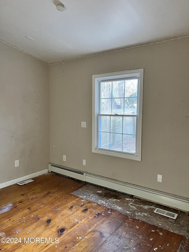 spare room with hardwood / wood-style flooring and a baseboard heating unit