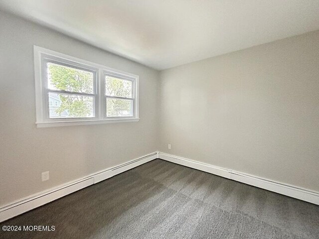 spare room with carpet and a baseboard heating unit