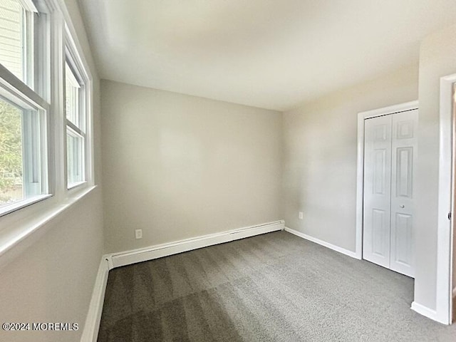 unfurnished room with dark colored carpet and baseboard heating