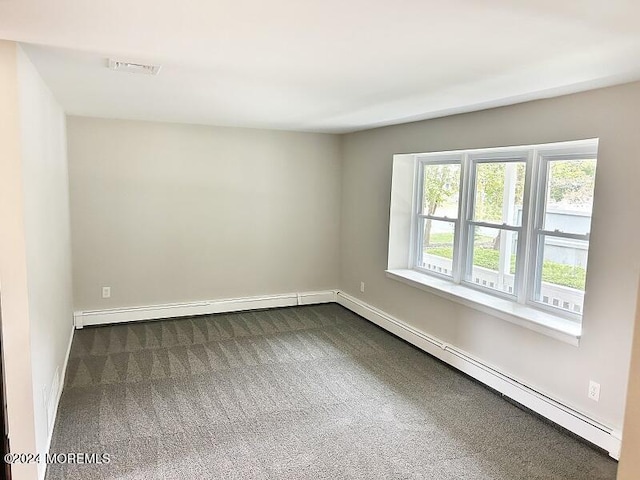 empty room featuring a wealth of natural light, a baseboard heating unit, and dark colored carpet