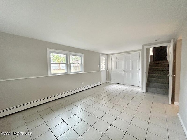 tiled empty room featuring a baseboard heating unit