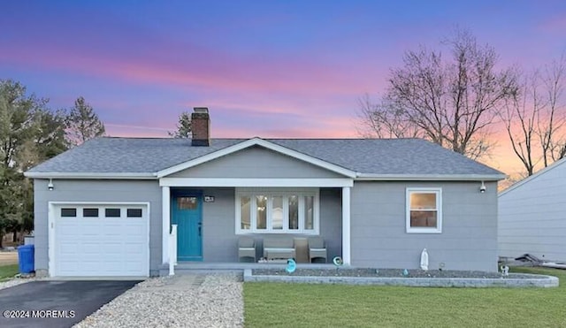 ranch-style home with a yard, covered porch, and a garage