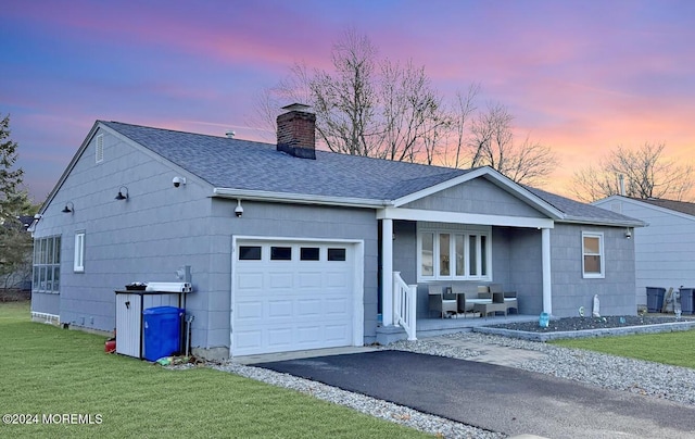 single story home with a garage, a lawn, and covered porch