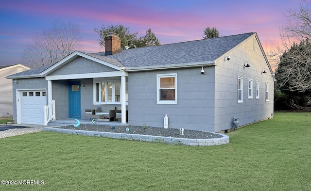 ranch-style home with a garage, covered porch, and a lawn