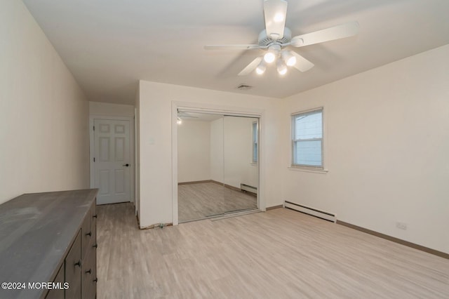 unfurnished bedroom with a baseboard heating unit, light hardwood / wood-style flooring, a closet, and ceiling fan