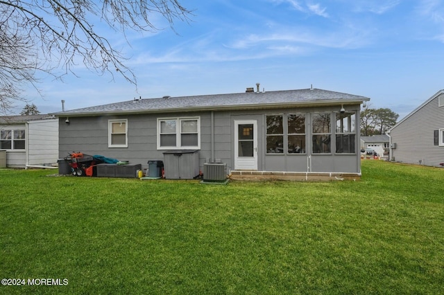 back of property with a sunroom, cooling unit, and a lawn