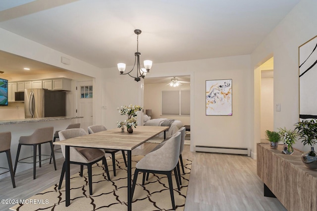 dining space featuring a baseboard heating unit, a notable chandelier, and light wood-type flooring