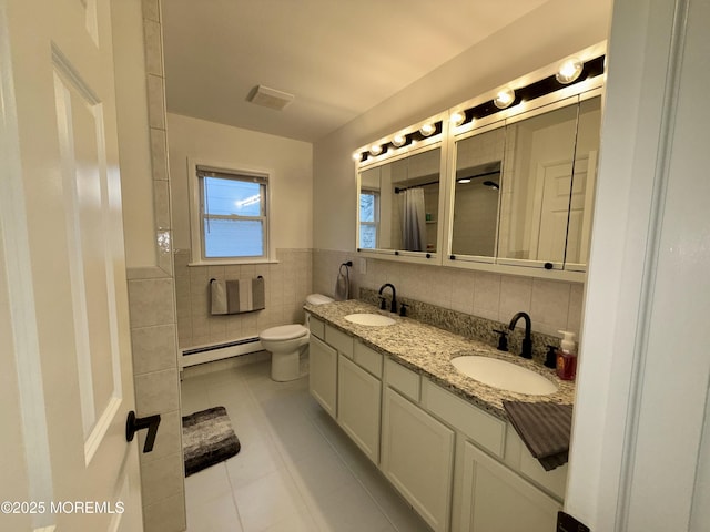 bathroom with a baseboard radiator, tile walls, tile patterned flooring, vanity, and toilet