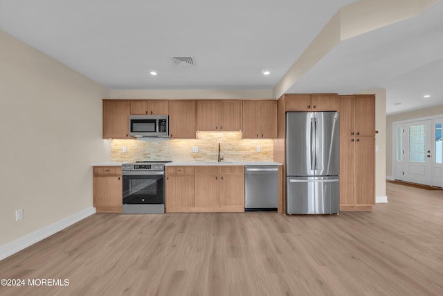 kitchen featuring decorative backsplash, sink, light wood-type flooring, and stainless steel appliances