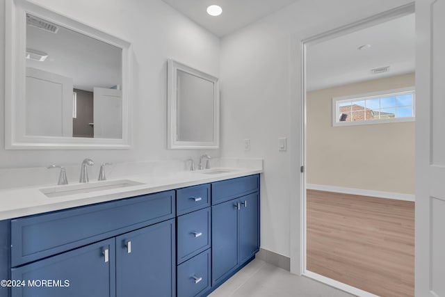 bathroom with double vanity, baseboards, and a sink