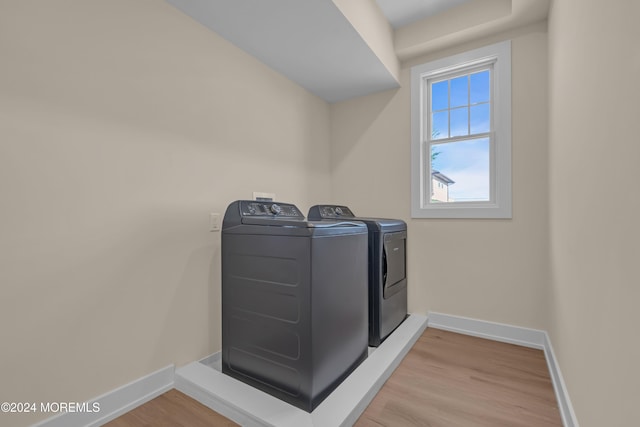 clothes washing area featuring baseboards, light wood-style flooring, laundry area, and washer and clothes dryer