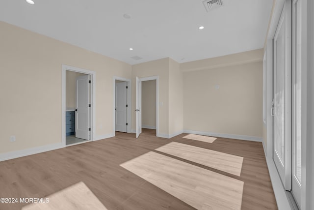 unfurnished bedroom with connected bathroom and light hardwood / wood-style floors