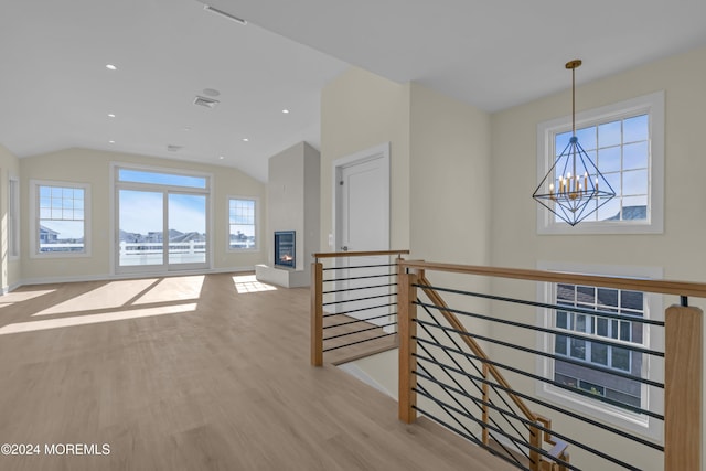 hall with a chandelier, vaulted ceiling, and light hardwood / wood-style flooring