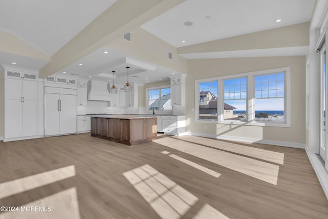 kitchen featuring custom exhaust hood, paneled built in fridge, a large island, white cabinetry, and a chandelier