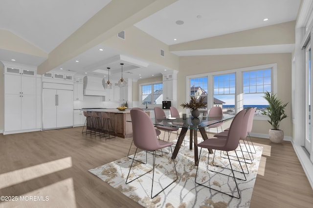 dining space featuring visible vents, light wood-style floors, and vaulted ceiling