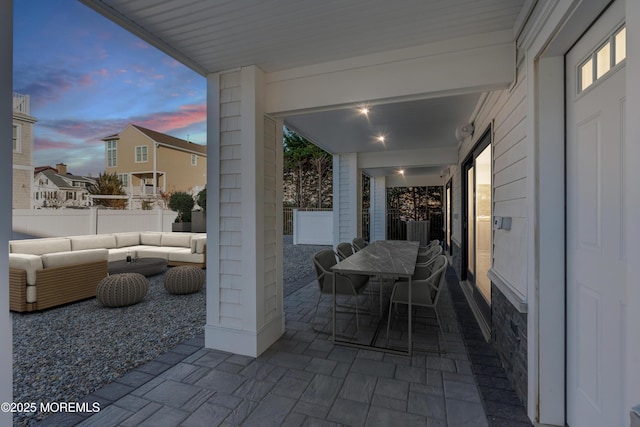 patio terrace at dusk with outdoor lounge area, outdoor dining area, and fence