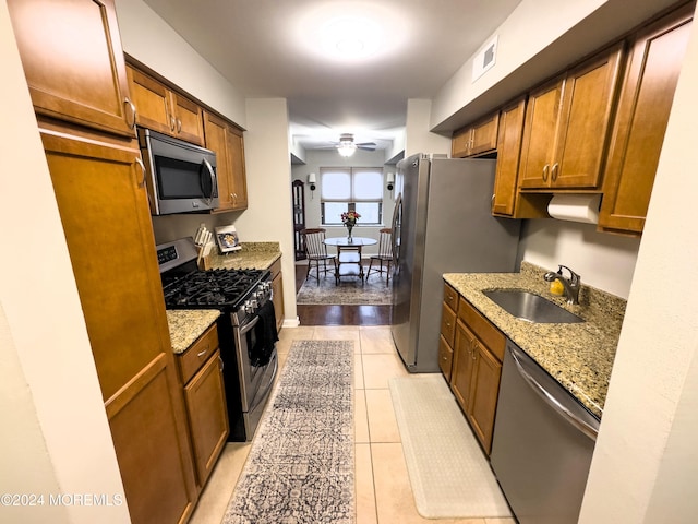 kitchen with sink, ceiling fan, light tile patterned floors, appliances with stainless steel finishes, and light stone counters