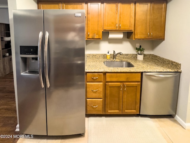 kitchen with stainless steel appliances, light stone counters, and sink