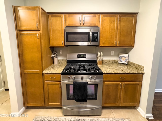 kitchen with light stone countertops, stainless steel appliances, and light tile patterned floors