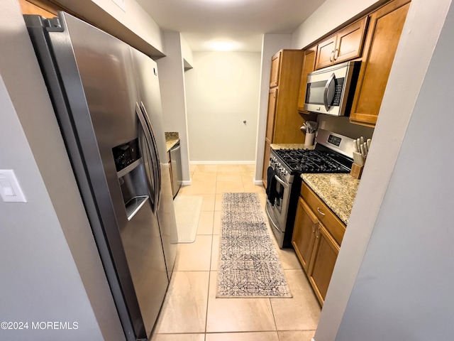 kitchen featuring light stone counters, light tile patterned floors, and stainless steel appliances