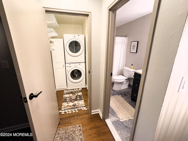 laundry area with dark hardwood / wood-style flooring and stacked washing maching and dryer