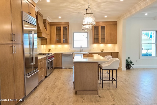 kitchen with a kitchen breakfast bar, premium range hood, ornamental molding, high end appliances, and a center island