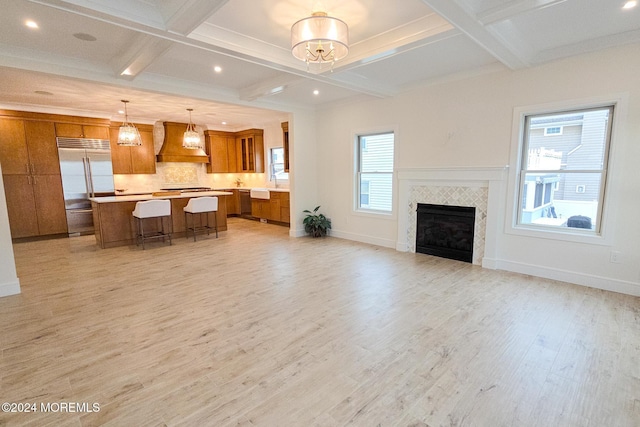 living room with a tile fireplace, beam ceiling, light wood-type flooring, and coffered ceiling