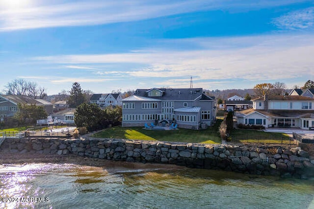 rear view of property featuring a yard, fence, a residential view, and a water view