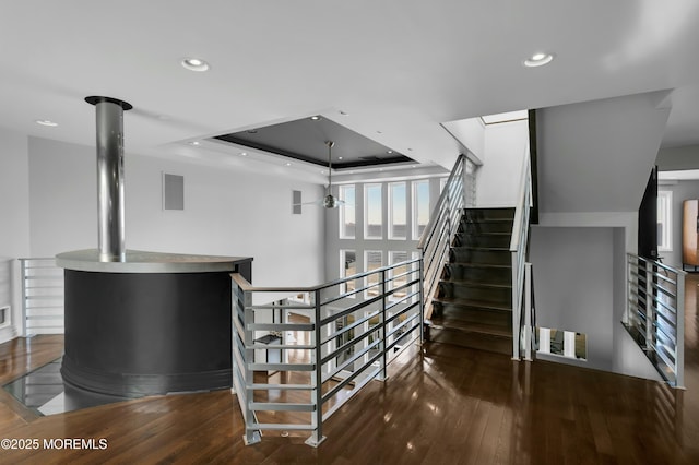 staircase with visible vents, a ceiling fan, wood finished floors, recessed lighting, and a raised ceiling