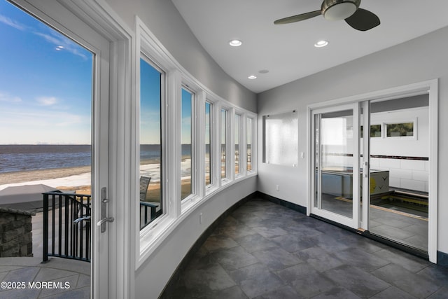 unfurnished sunroom with french doors, a water view, and ceiling fan