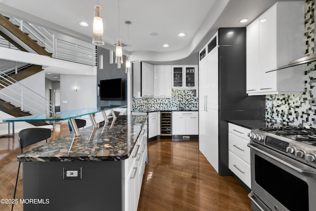 kitchen with pendant lighting, a breakfast bar, decorative backsplash, gas range, and dark wood-style flooring