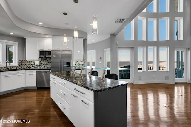 kitchen with tasteful backsplash, visible vents, dark wood-type flooring, appliances with stainless steel finishes, and a sink