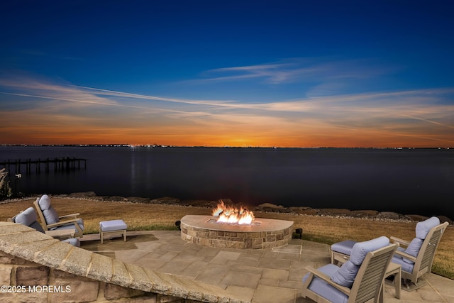 patio terrace at dusk with a water view and a fire pit