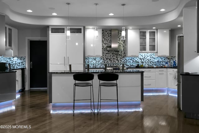 kitchen featuring glass insert cabinets, white cabinets, modern cabinets, and wall chimney exhaust hood