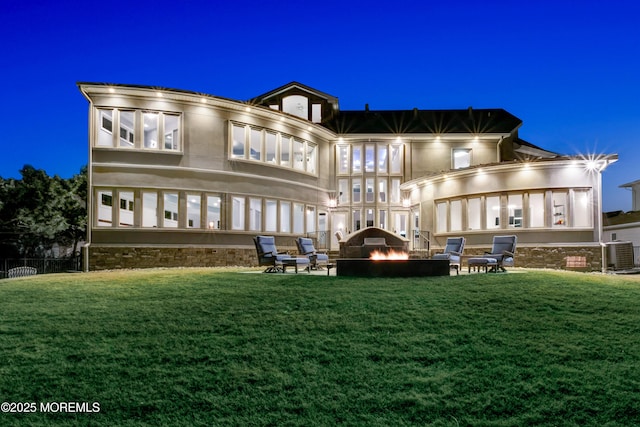 back of house at twilight with a patio area, a lawn, a fire pit, and central AC