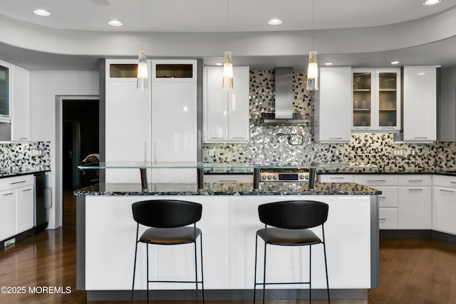 kitchen with tasteful backsplash, a kitchen breakfast bar, dark wood-style floors, white cabinetry, and wall chimney exhaust hood