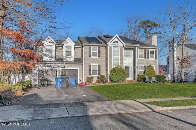 multi unit property with solar panels, a front yard, and a garage