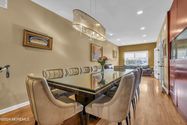 dining area with an inviting chandelier and light hardwood / wood-style flooring