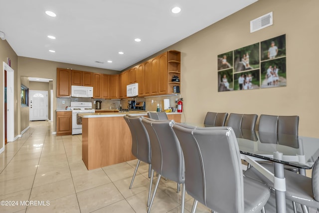 kitchen featuring kitchen peninsula, light tile patterned floors, and white appliances