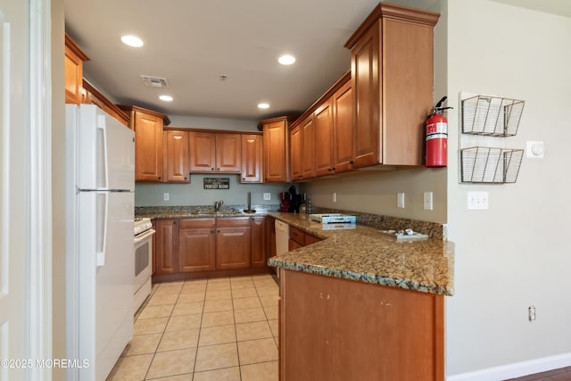 kitchen featuring light tile patterned flooring, sink, dark stone countertops, and white appliances