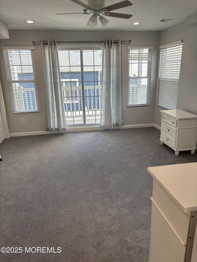 carpeted spare room featuring plenty of natural light and ceiling fan