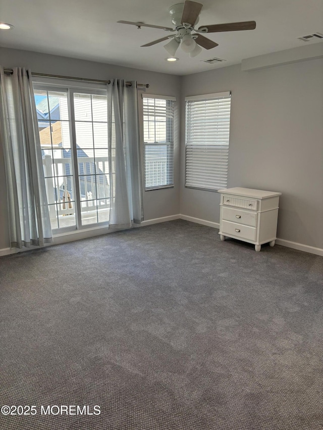 empty room with plenty of natural light, ceiling fan, and carpet