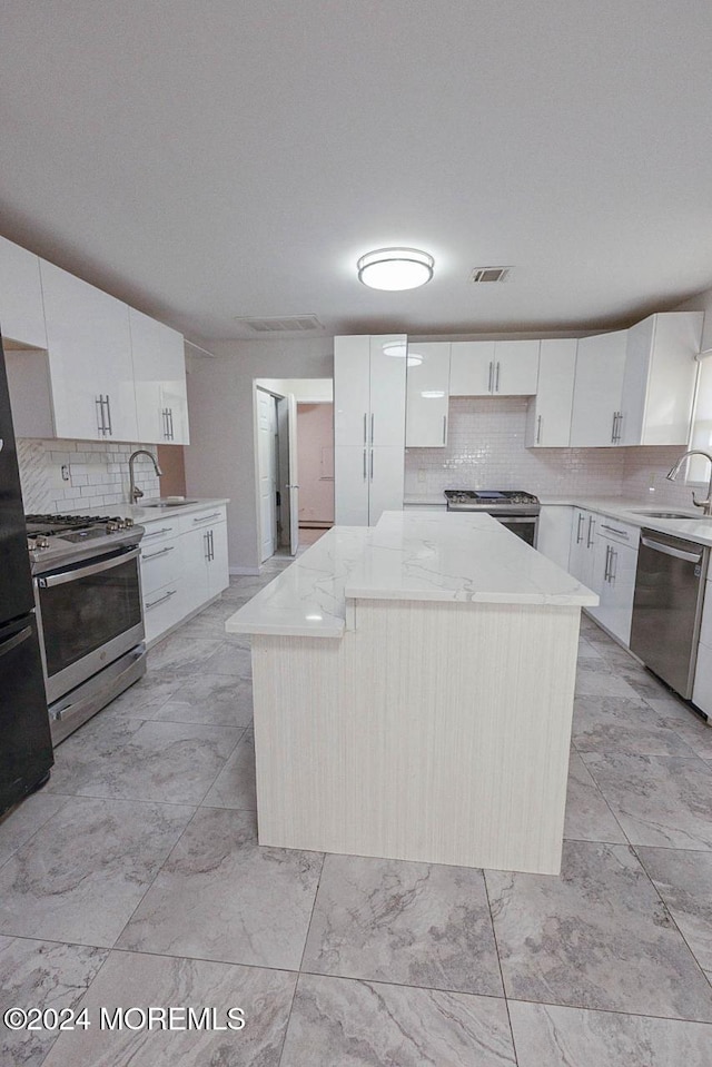 kitchen with a center island, white cabinetry, sink, and appliances with stainless steel finishes