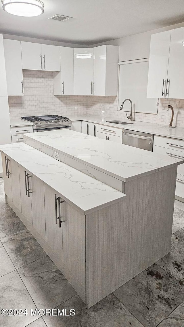 kitchen with a kitchen island, sink, white cabinetry, and stainless steel appliances