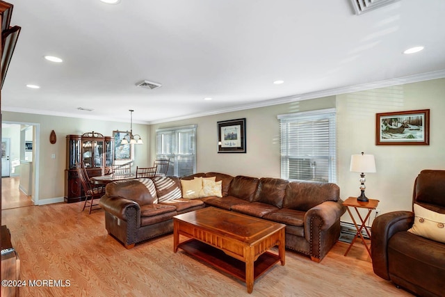 living room with baseboard heating, crown molding, light hardwood / wood-style flooring, and a notable chandelier