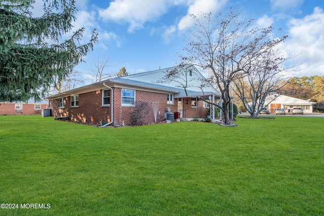 back of property with central AC and a lawn