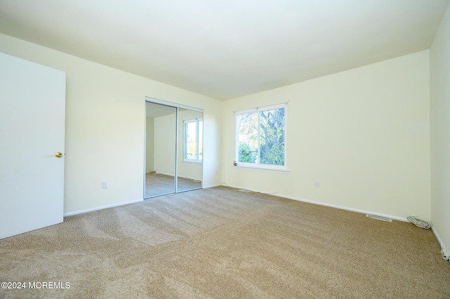 unfurnished bedroom with a closet and light colored carpet