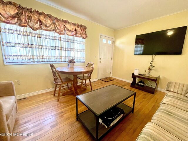 living room with wood-type flooring and ornamental molding